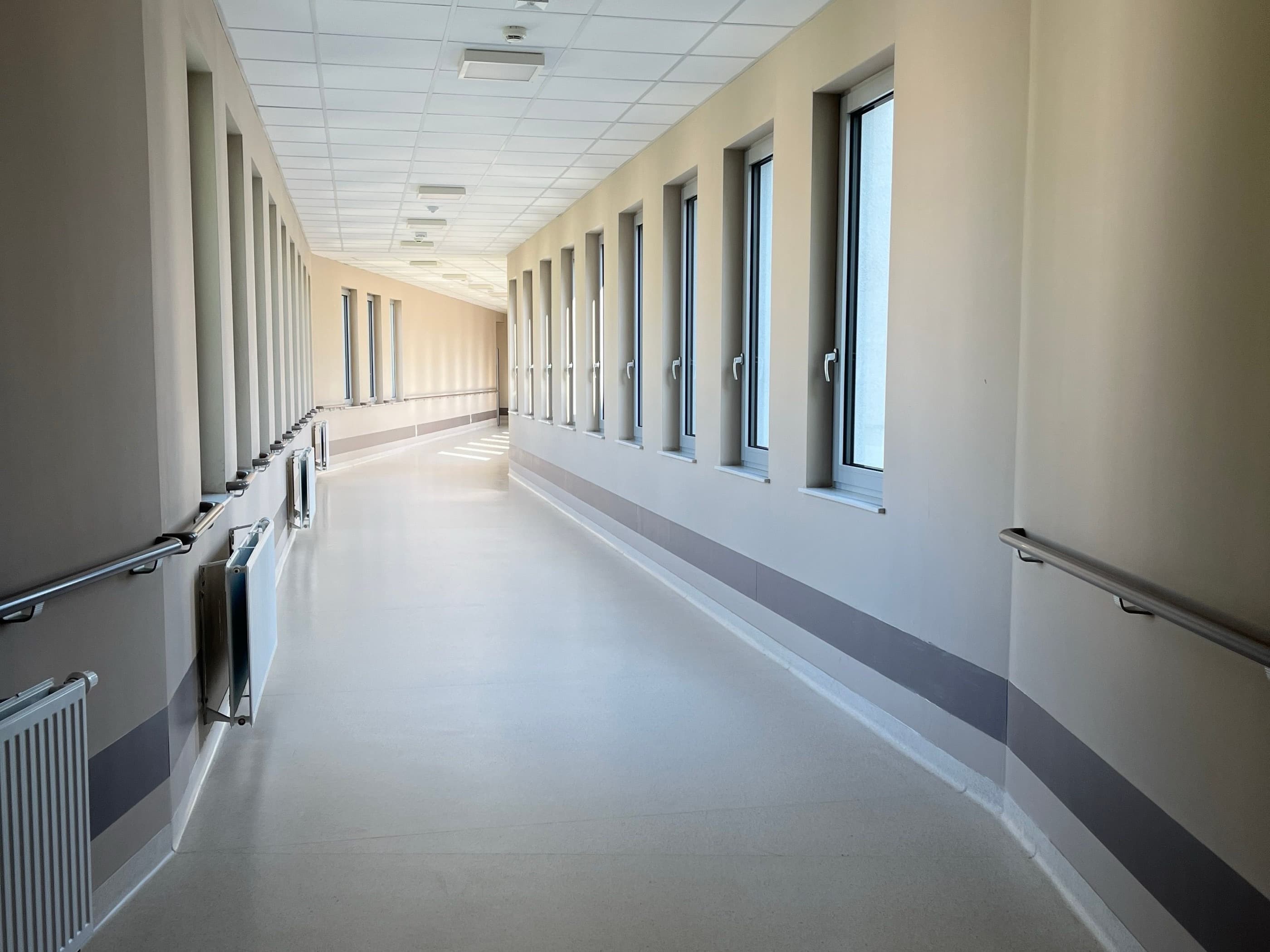 A hospital corridor lit by a row of windows